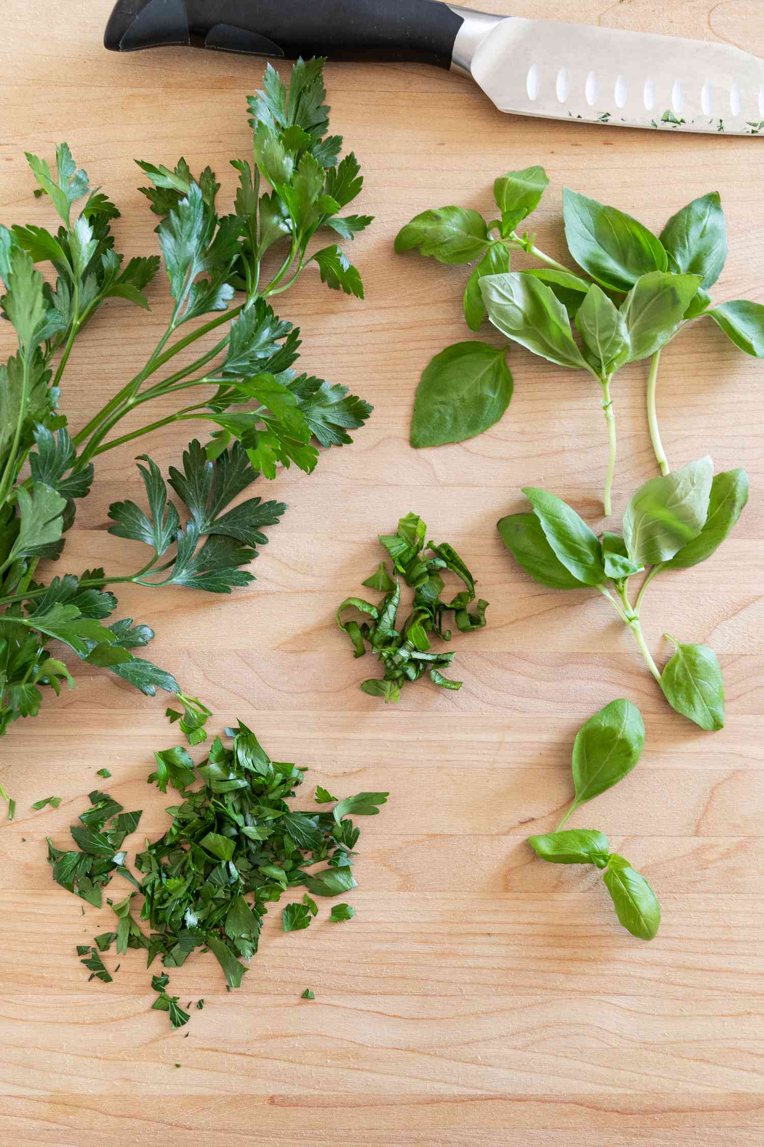 Fresh parsley, basil chopped with a knife on a cutting board