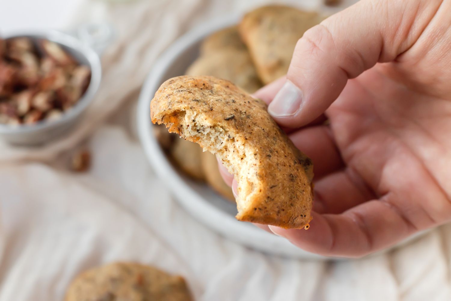 A person holding a banana bread cookie with a bite taken.