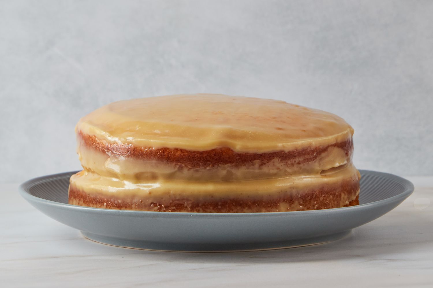 A layered sour cream cake with frosting served on a plate for Reese Witherspoon's Sour Cream Cake