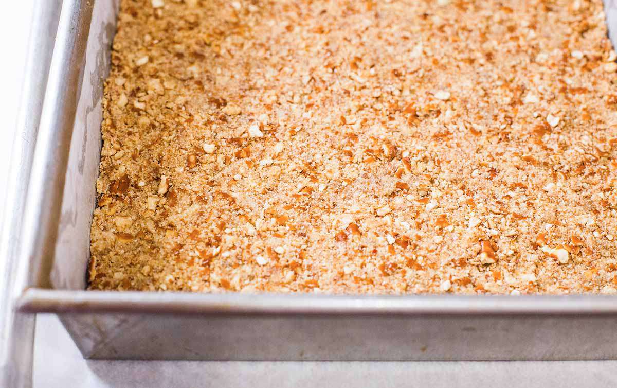 Magic Cookie Bars with Peanut Butter and Pretzels press the crust into the pan