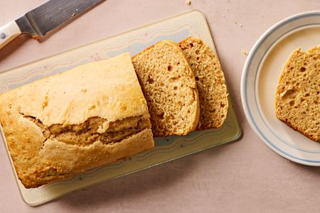Overhead view of a loaf of retro peanut butter bread next to a plate with a slice
