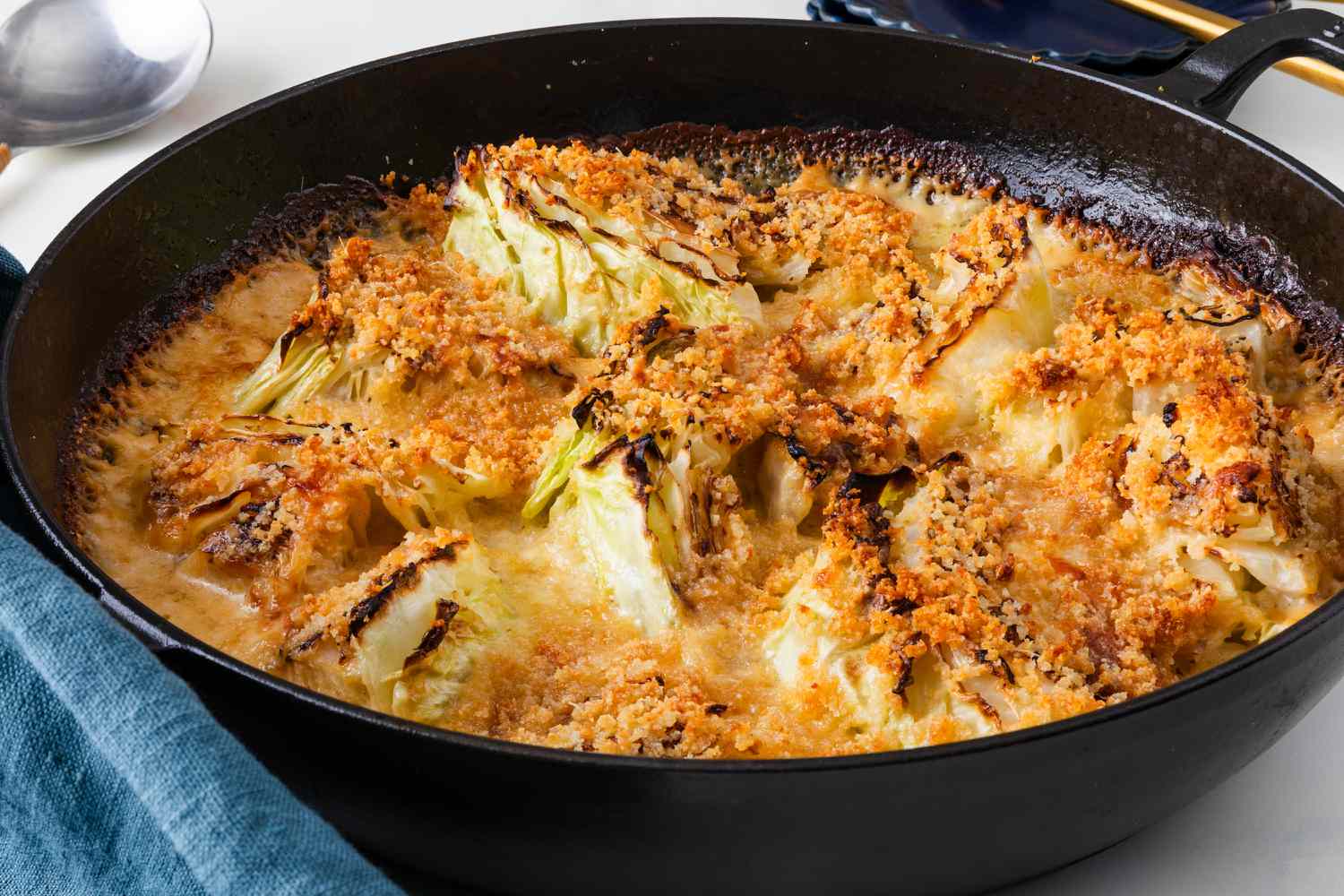 Angled view of a cast iron skillet of cabbage au gratin after baking