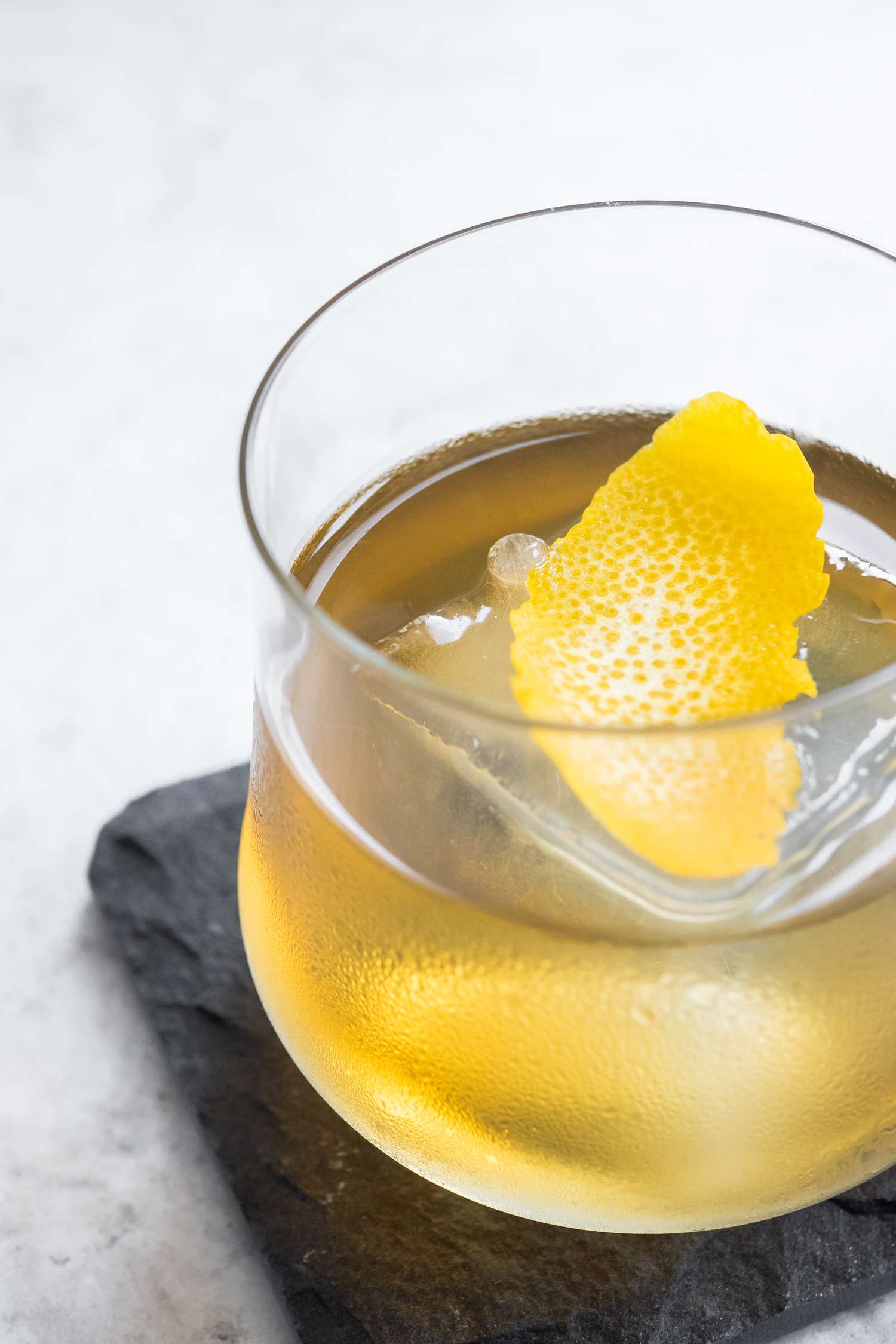 Rusty Nail on a Granite Coaster Garnished with Lemon Peel