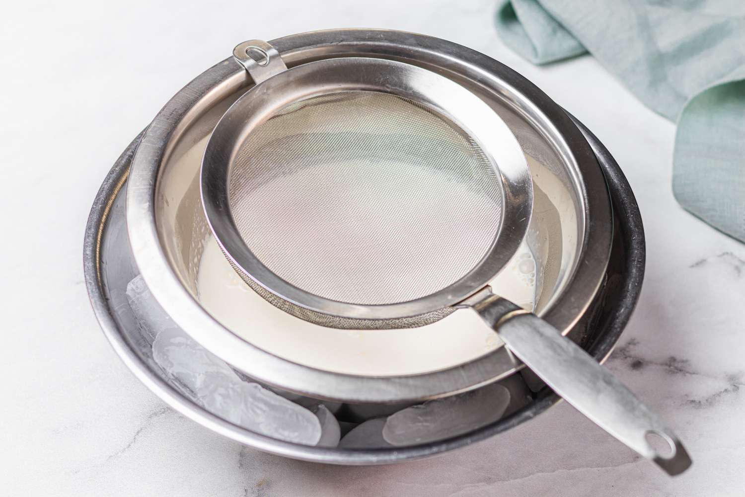 Chilling the cream in a bowl of ice with a strainer set on top to make a homemade ice cream recipe.