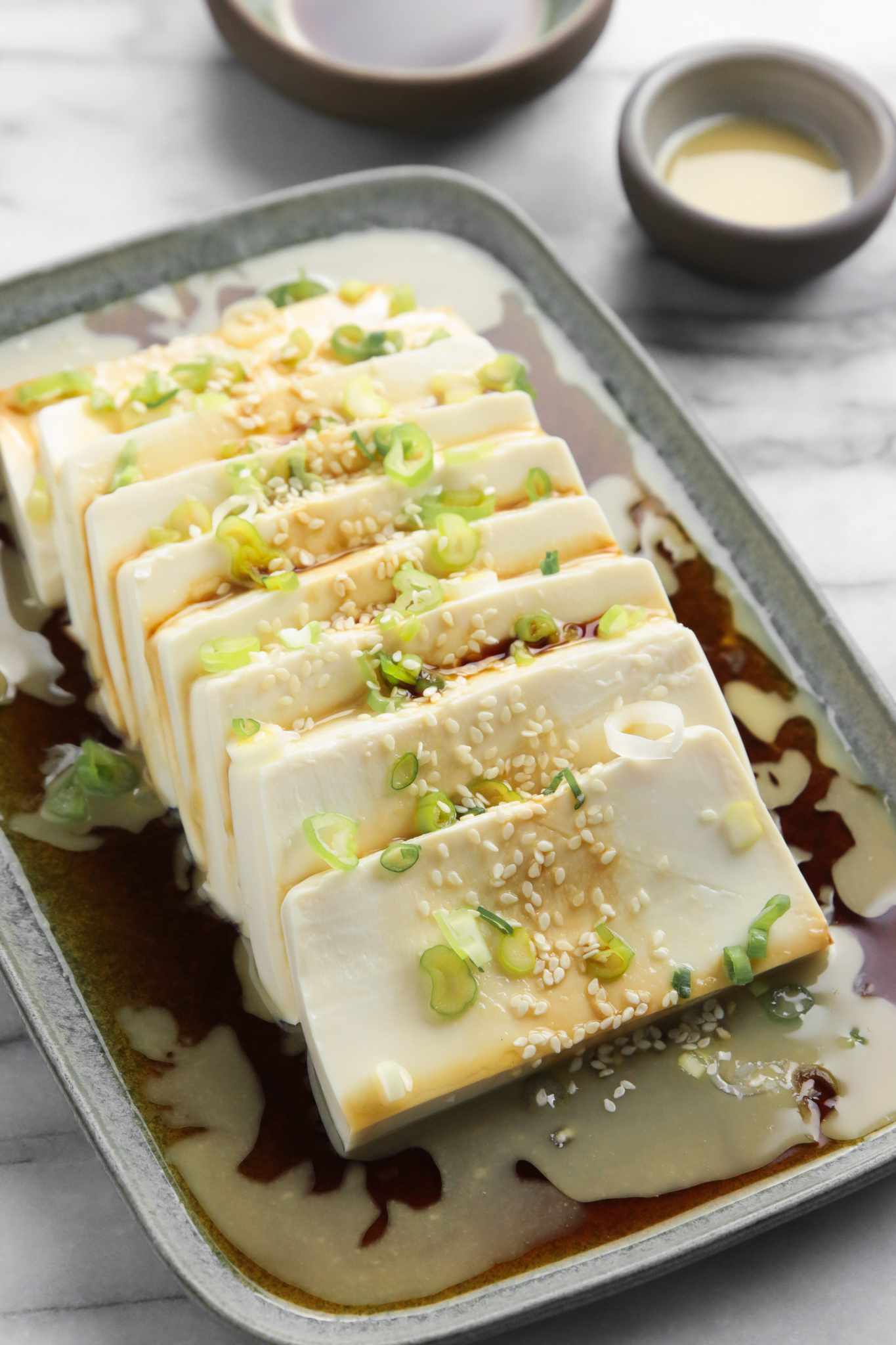 Close Up: Platter of Silken Tofu with Sesame Soy Sauce Next to a Small Bowl with More Soy Sauce and Another Small Bowl with Sesame Sauce