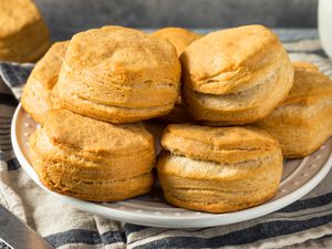A white plate with buttermilk biscuits stacked high