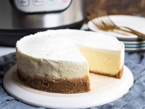 Cheesecake with a slice cut out sitting in front of an Instant pot