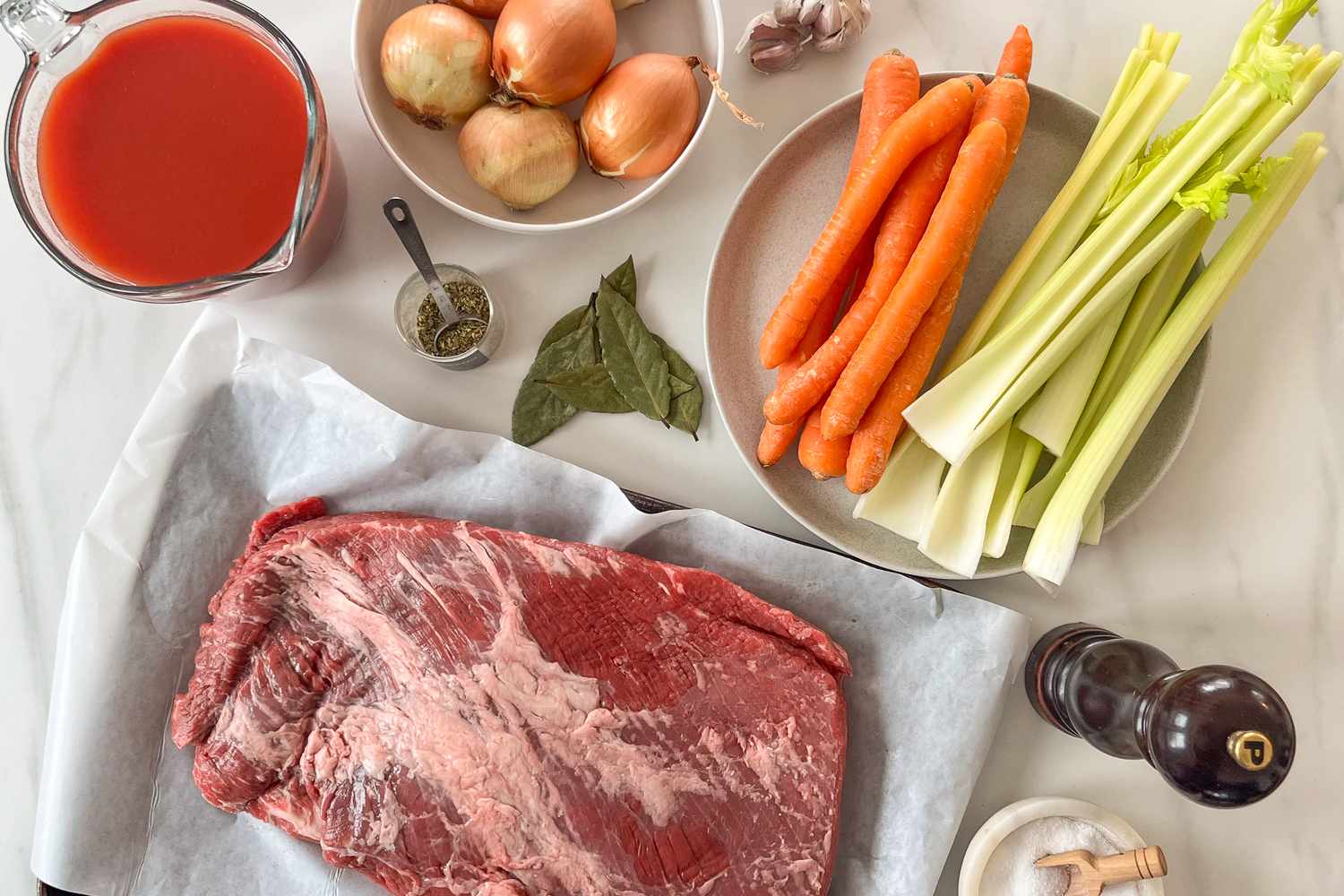 Ingredients for making brisket including raw meat vegetables and seasonings
