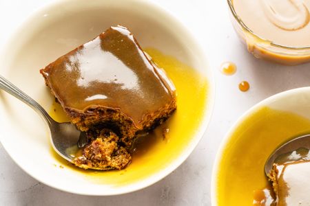 Sticky toffee pudding served in bowls with a spoon