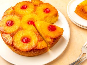 Easy Pineapple Upside Down Cake on a plate, one slice removed, another slice cut