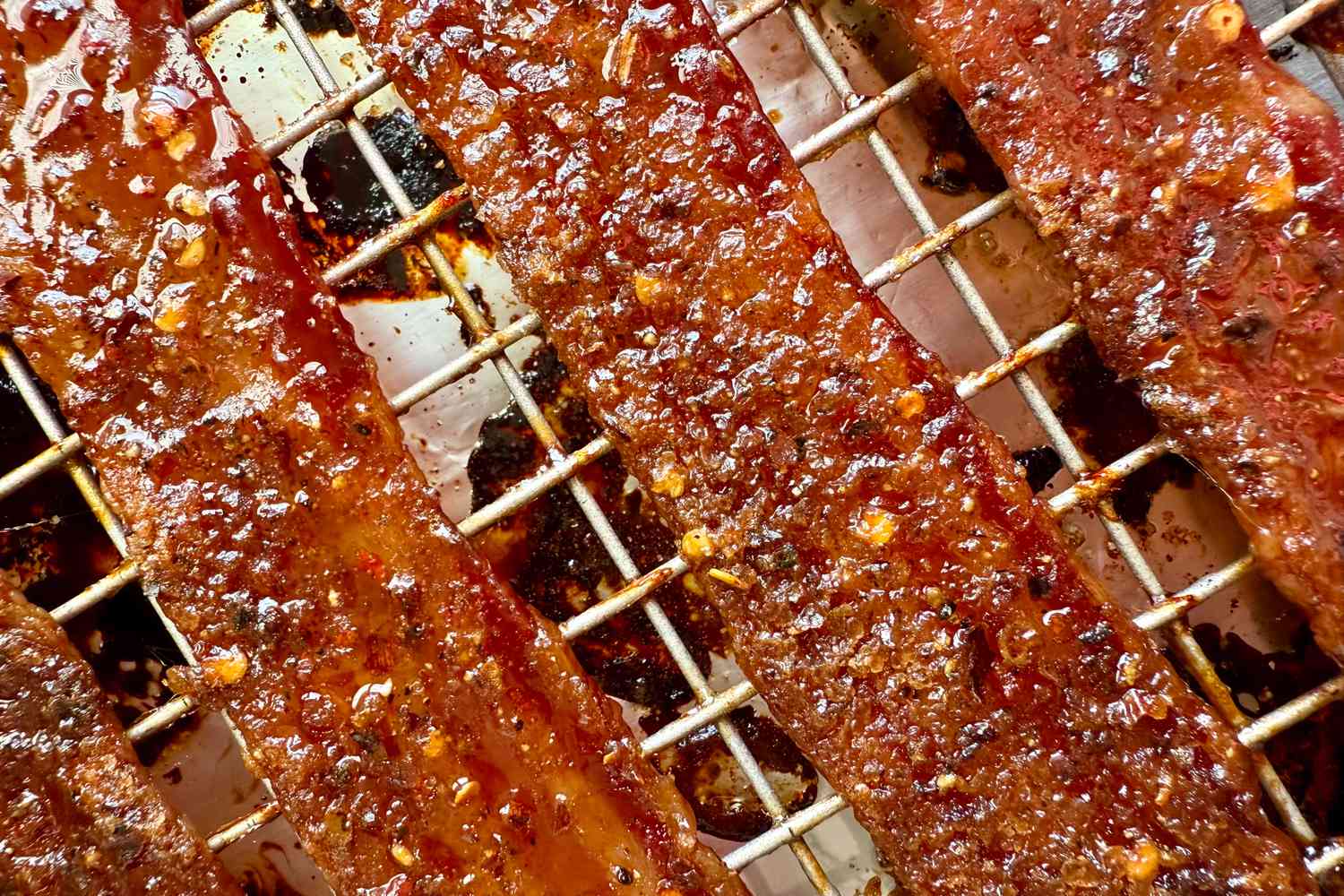 Candied bacon strips on a cooling rack