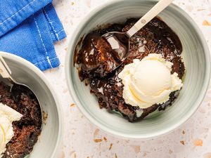 Two bowls with a serving each of southern chocolate cobbler, and topped with a scoop of vanilla ice cream