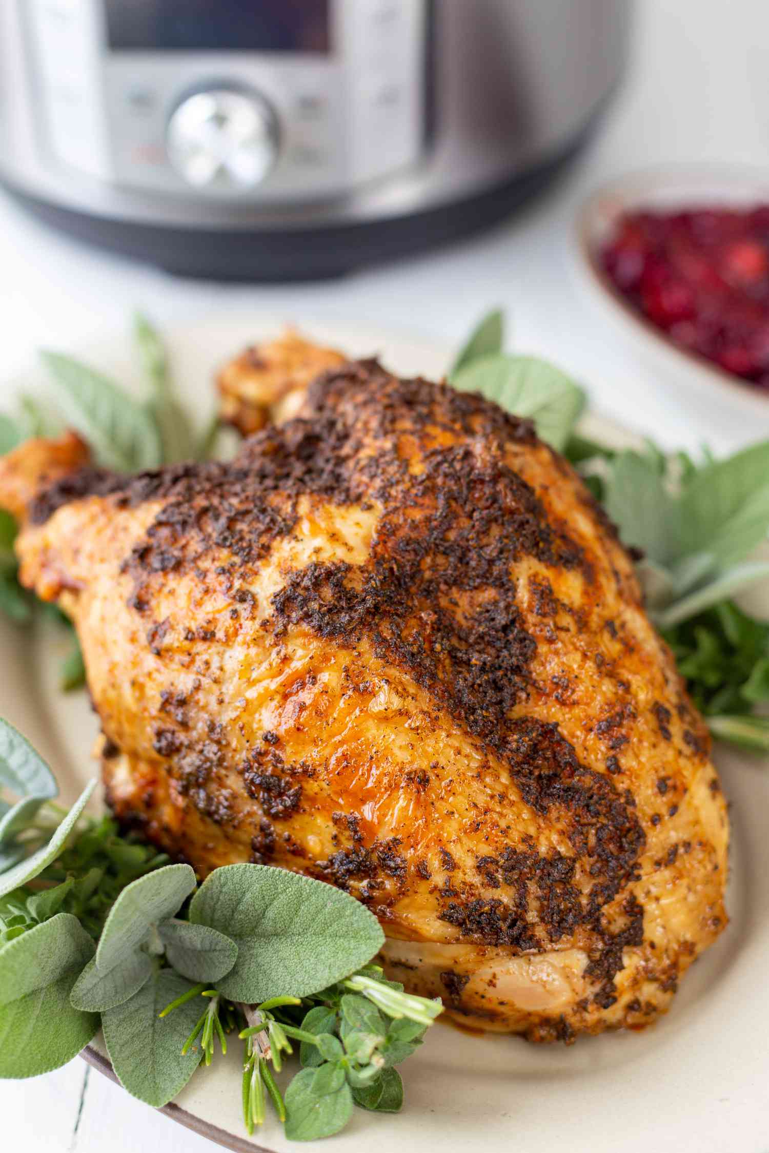 Quick and easy instant pot turkey breasts set in front of an instant pot on an herb covered platter.