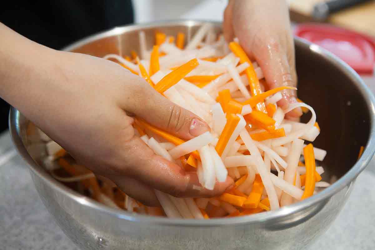 massage sugar and salt into carrots and daikon for vietnamese do chua pickles