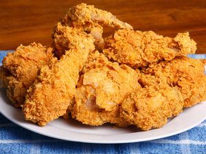 A plate of fried chicken pieces on a blue checkered cloth