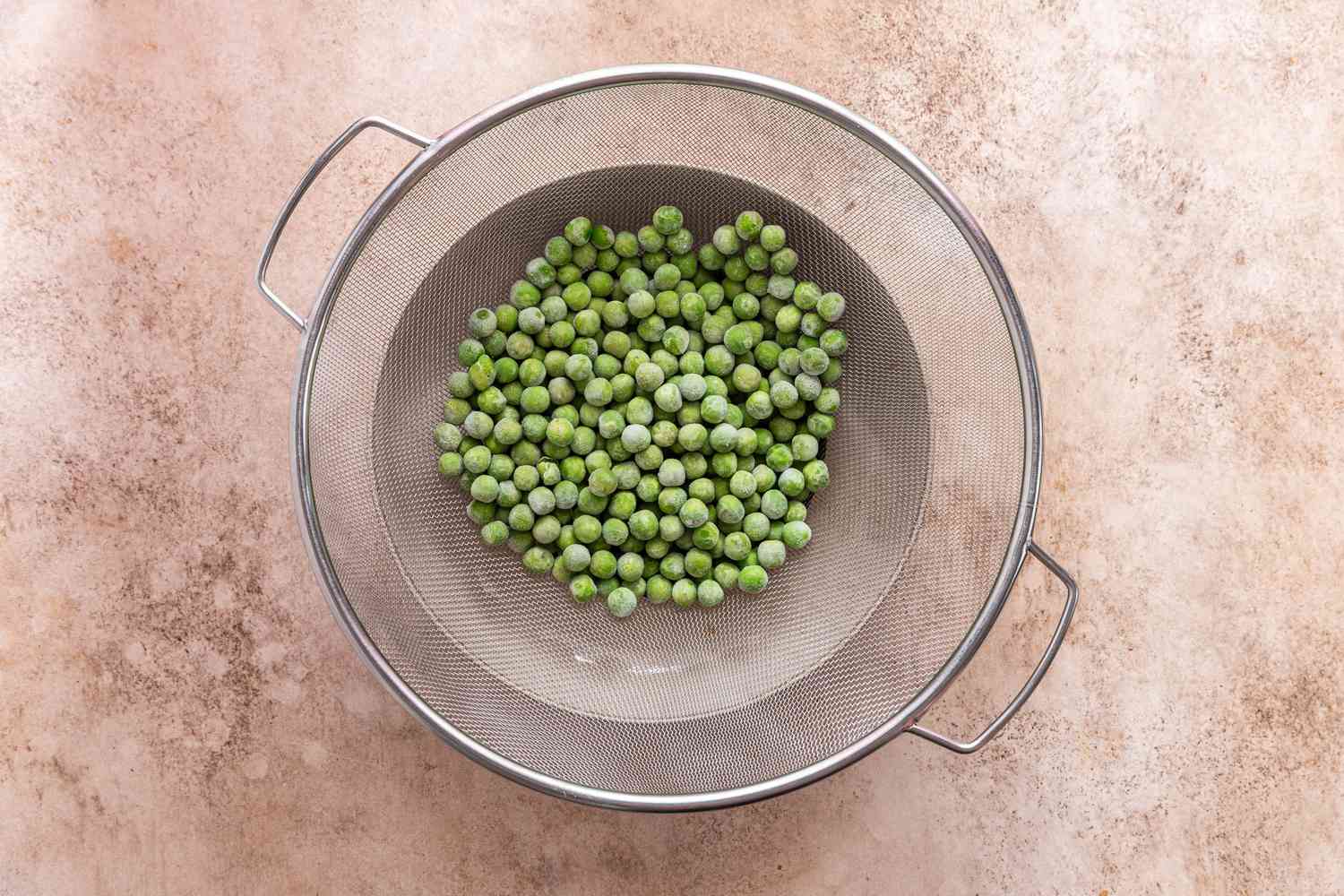 Frozen Peas in a Colander Over a Bowl for Creamy Cavatappi Recipe