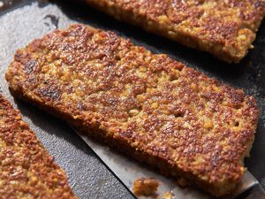 Sliced Goetta on a Griddle With a Spatula Slide Under One Piece 