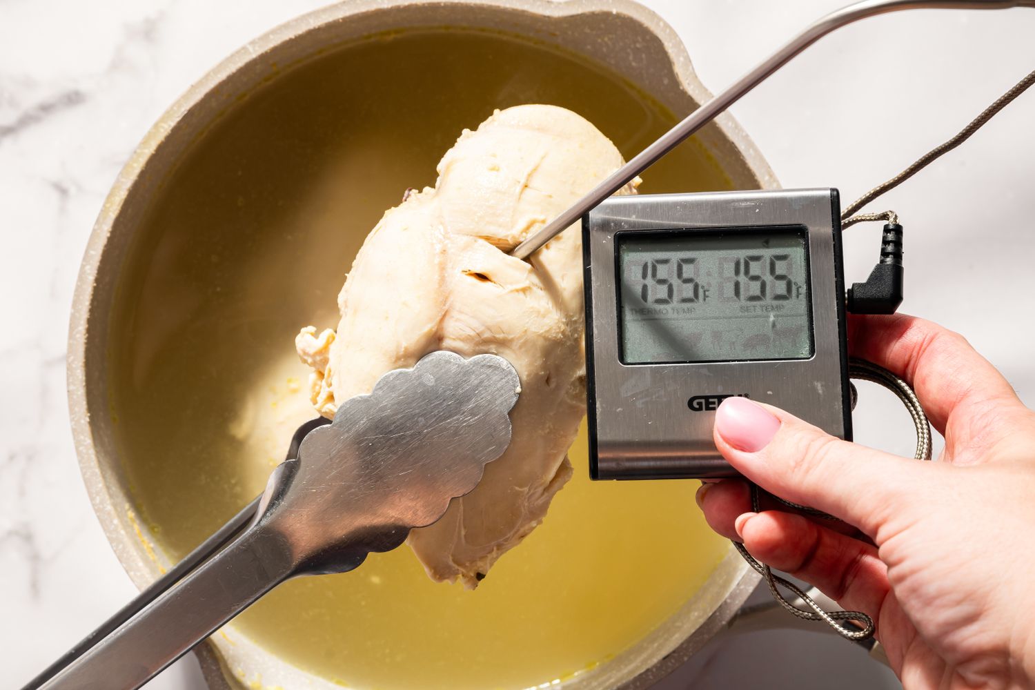 Overhead view of checking the temperature of a chicken breast with an instant-read thermometer for Moravian Chicken Pie recipe