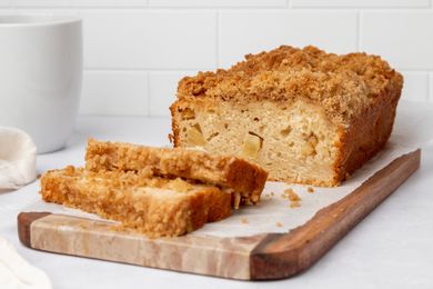A loaf of homemade apple bread with a few slices cut and laid in front of the loaf.