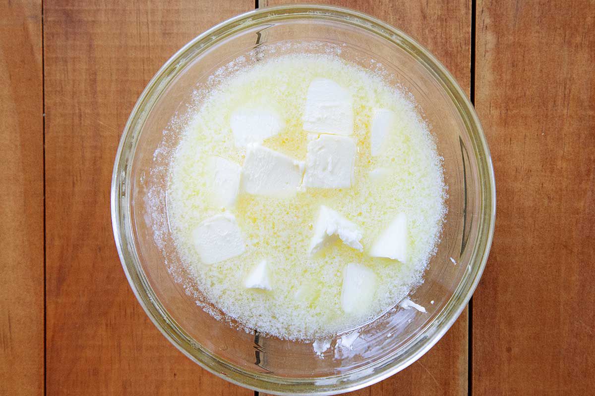 Partially melten butter in a glass bowl on a wooden table.