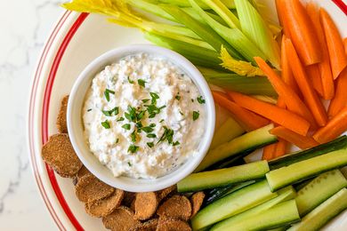 Spiced Cottage Cheese Dip in a bowl with veggies/melba toast around it