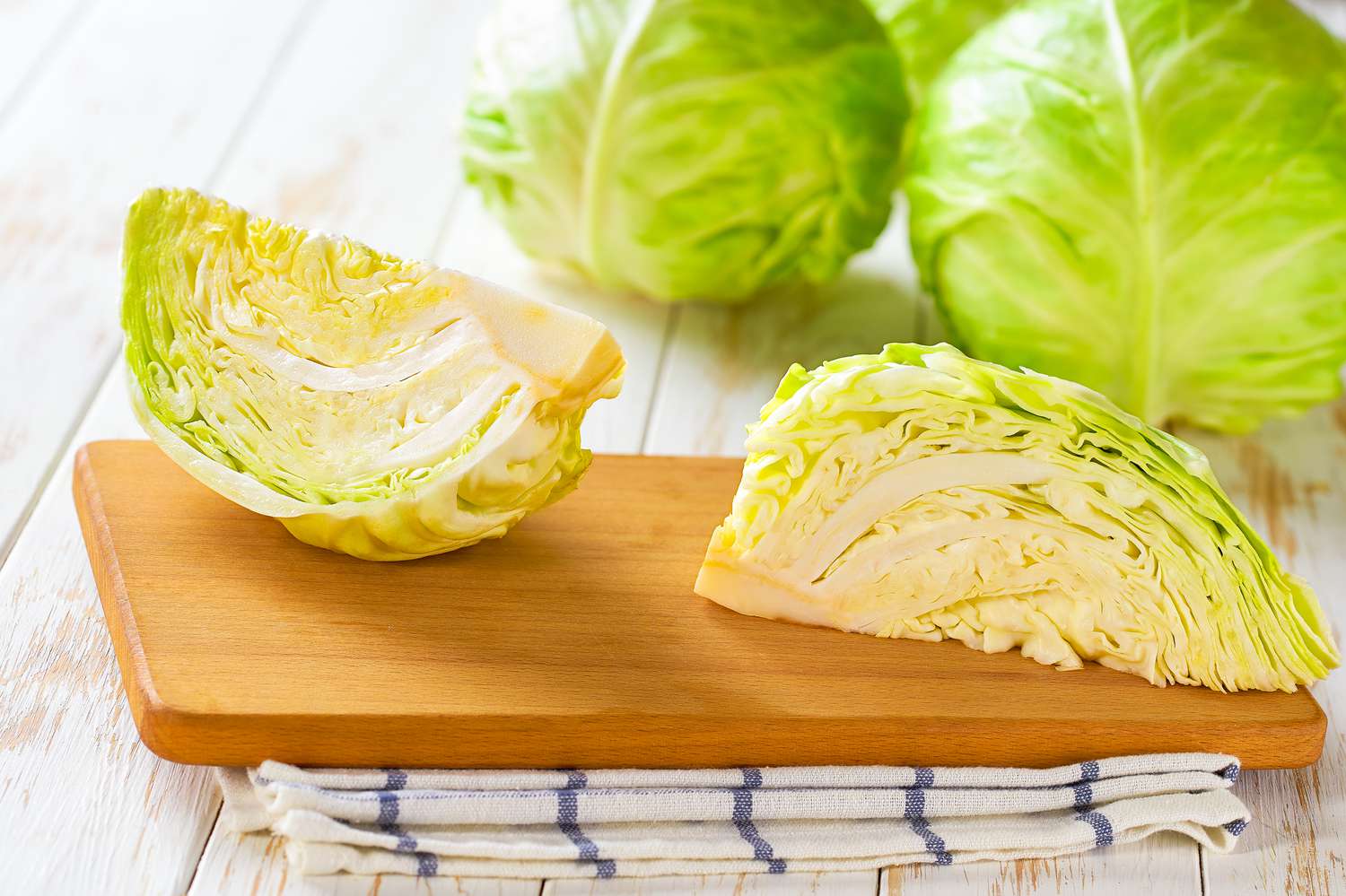Side view of green cabbage cut in half on a wooden cutting board