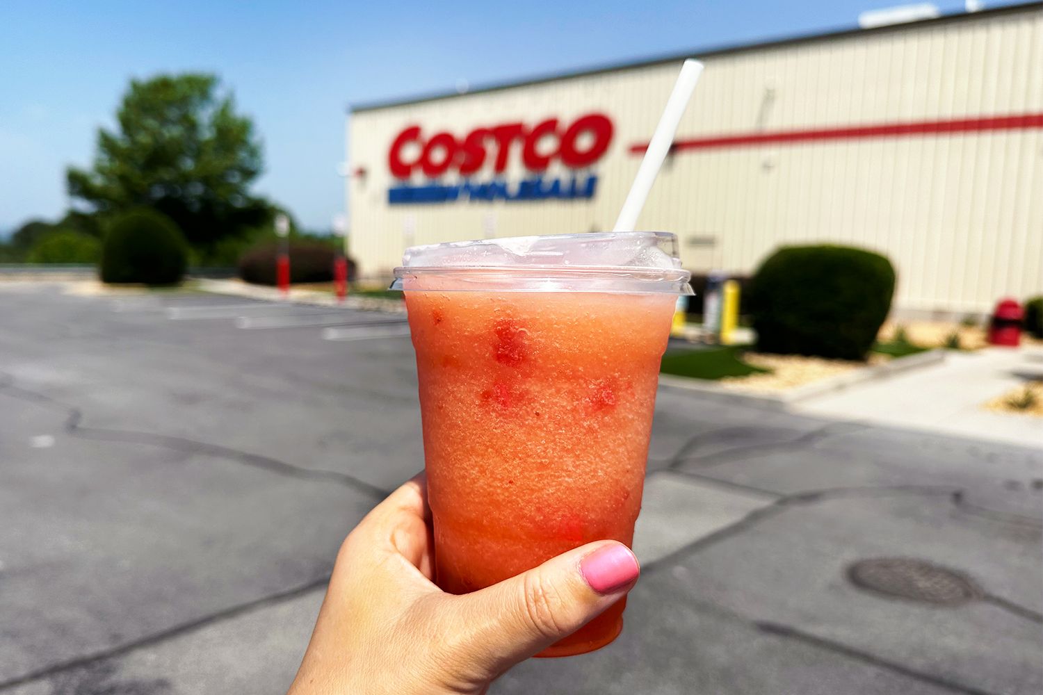 hand holding Costco Frozen Strawberry Lemonade Smoothie in front of a Costco