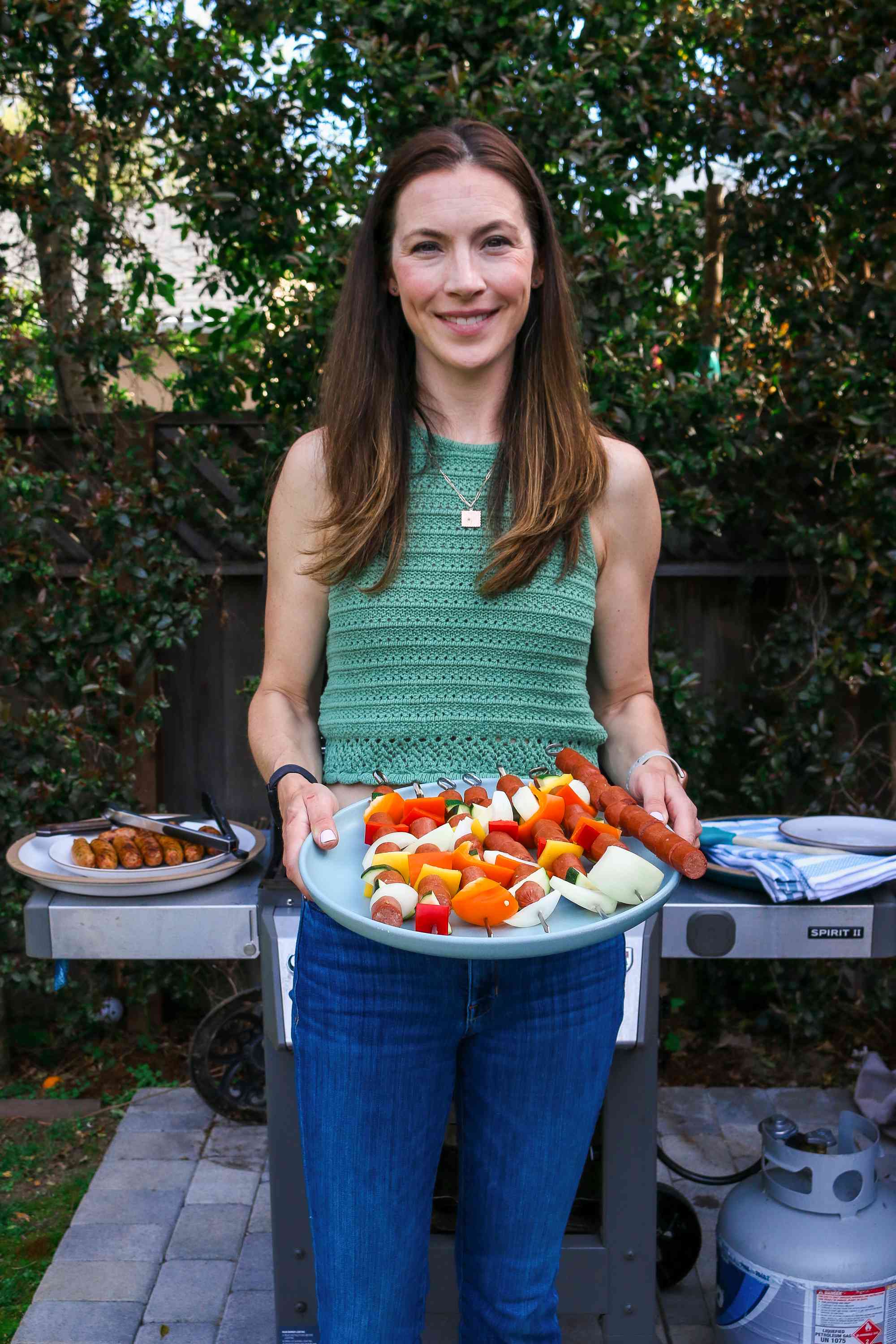 Shannon Pfeffer holding a platter of meat and vegetable skewers, ready to be grilled