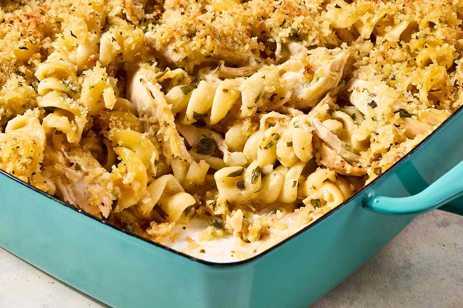 A casserole dish with a chicken piccata and noodle bake topped with breadcrumbs