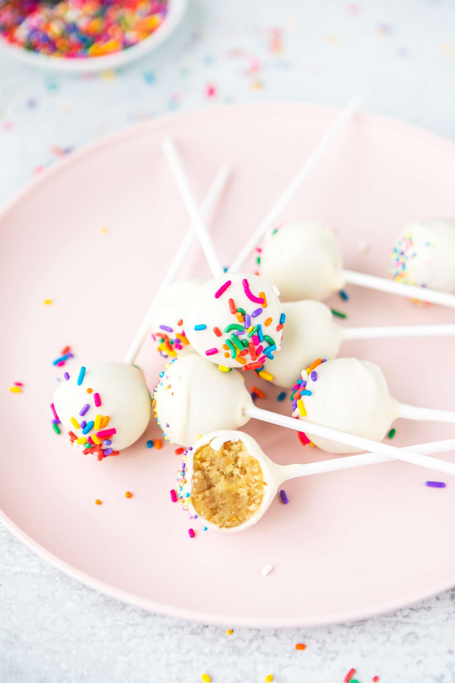 Cake Pops with Sprinkles on a Plate with One Partially Eaten