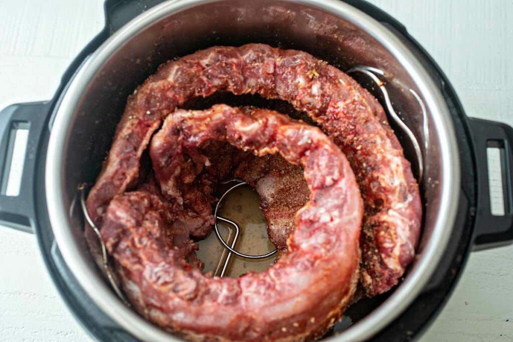 Raw rack of BBQ baby back ribs in the Instant Pot bowl