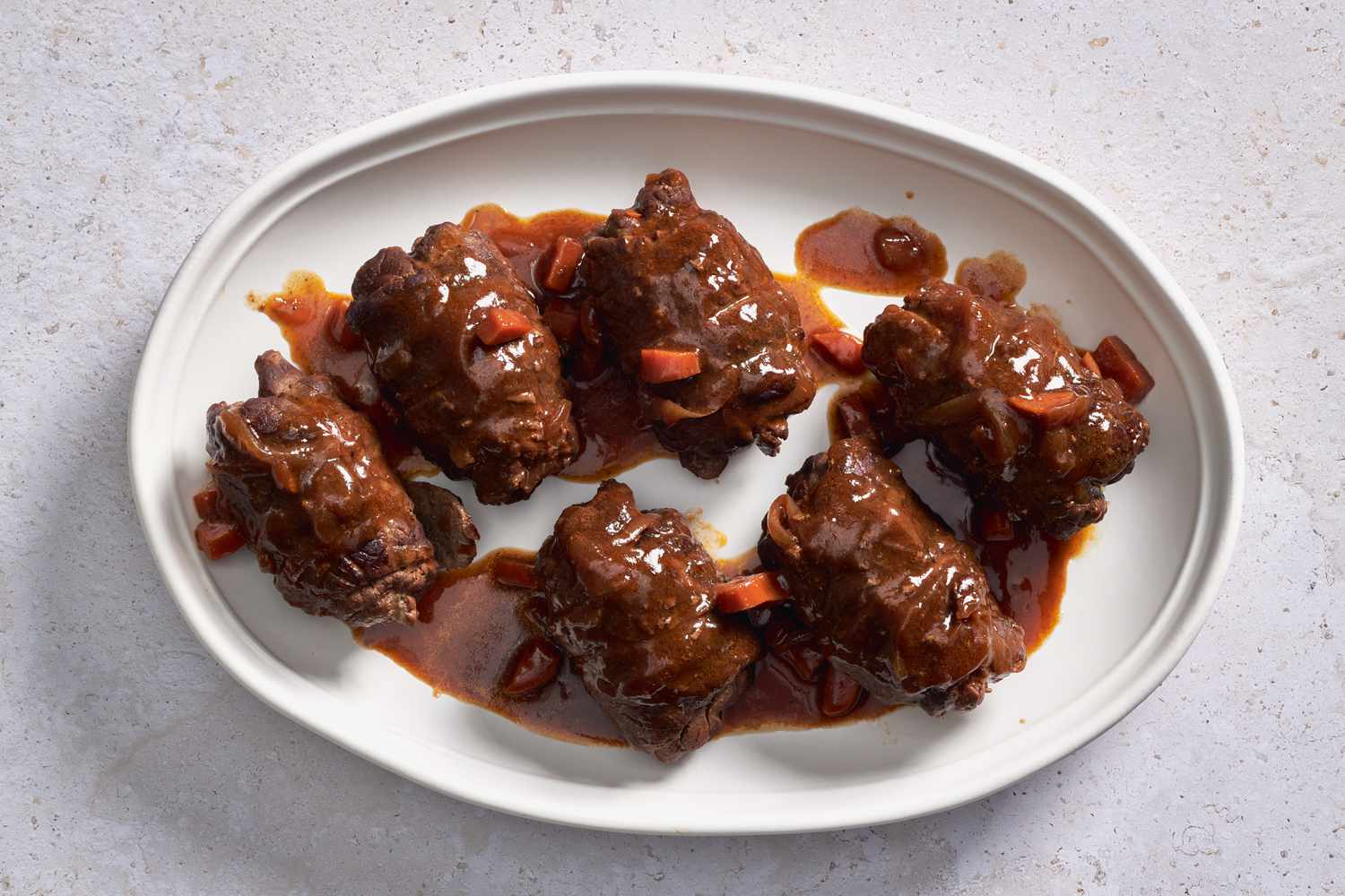 Rouladen on a platter with some of the braising sauce