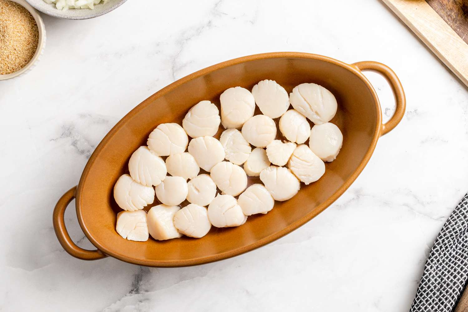 Raw scallops in a dish to bake