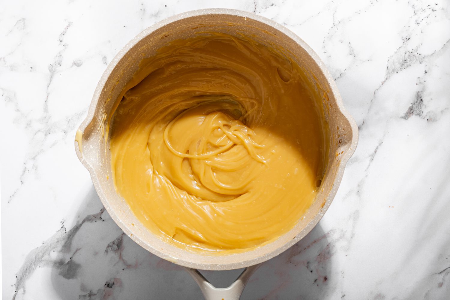 Overhead view of a saucepan with the caramel mixture heated for Millionaire Shortbread recipe
