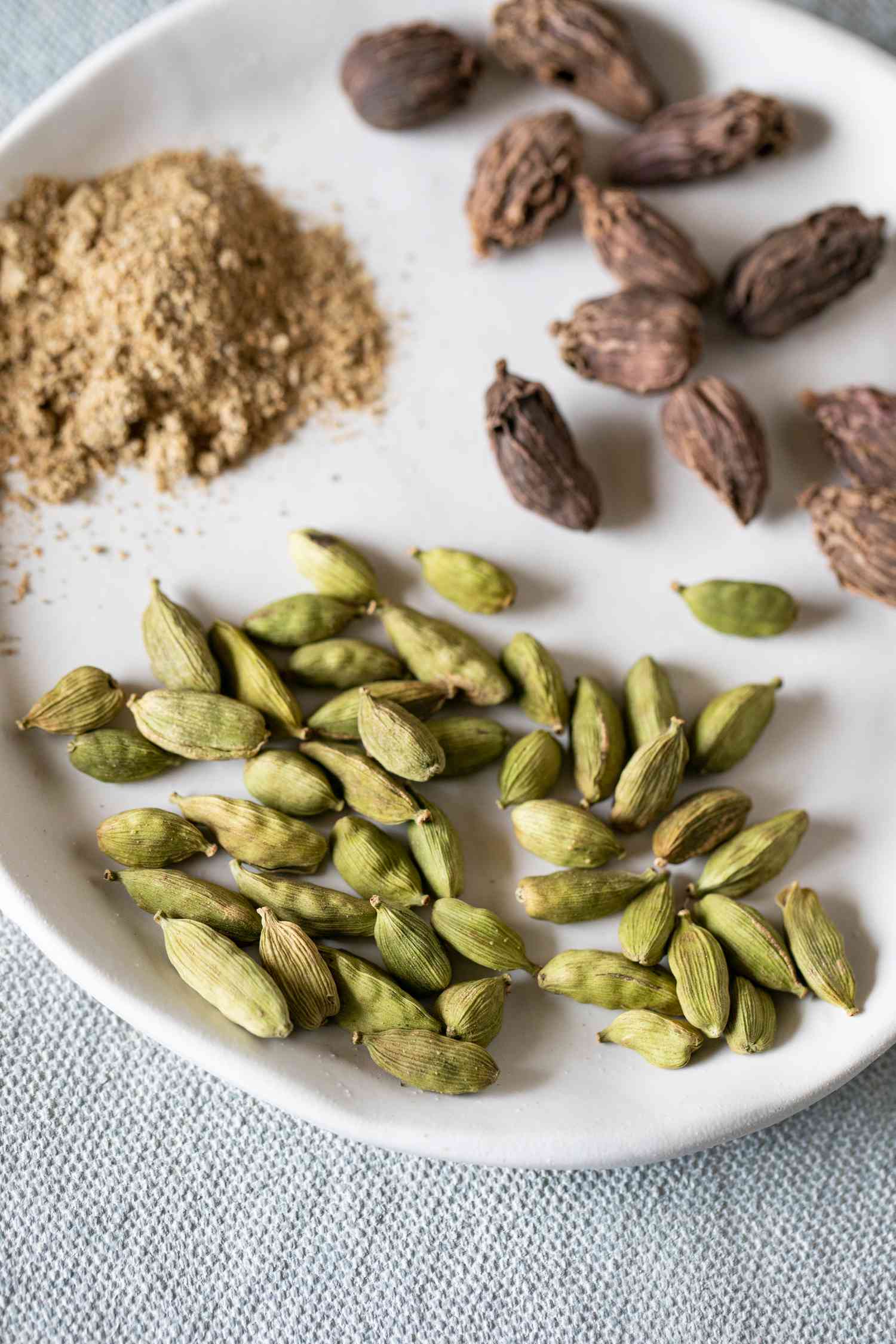Close up of green cardamom pods on white platter