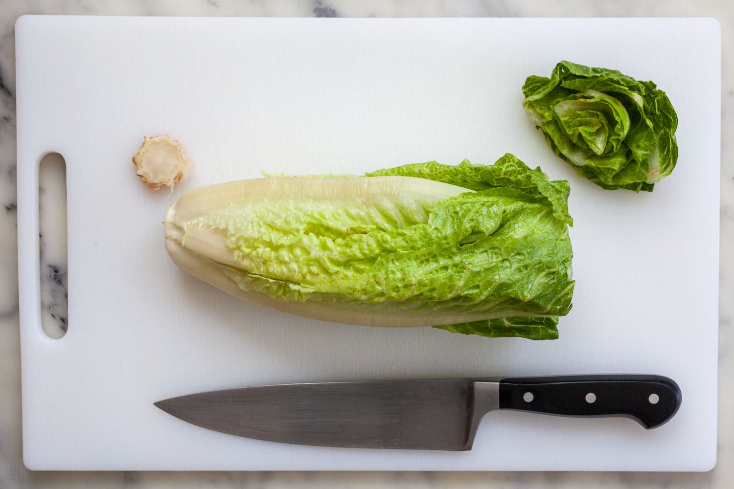 Cutting board with romaine heart with the top and ends sliced.