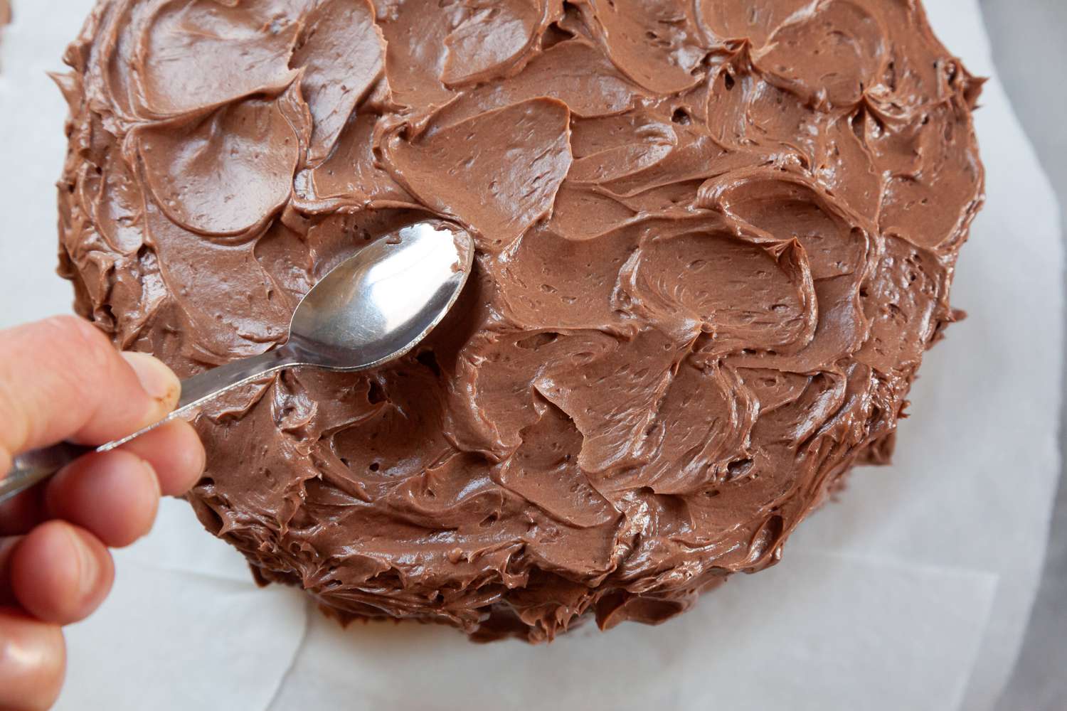 Using a spoon to show a cake frosting technique.
