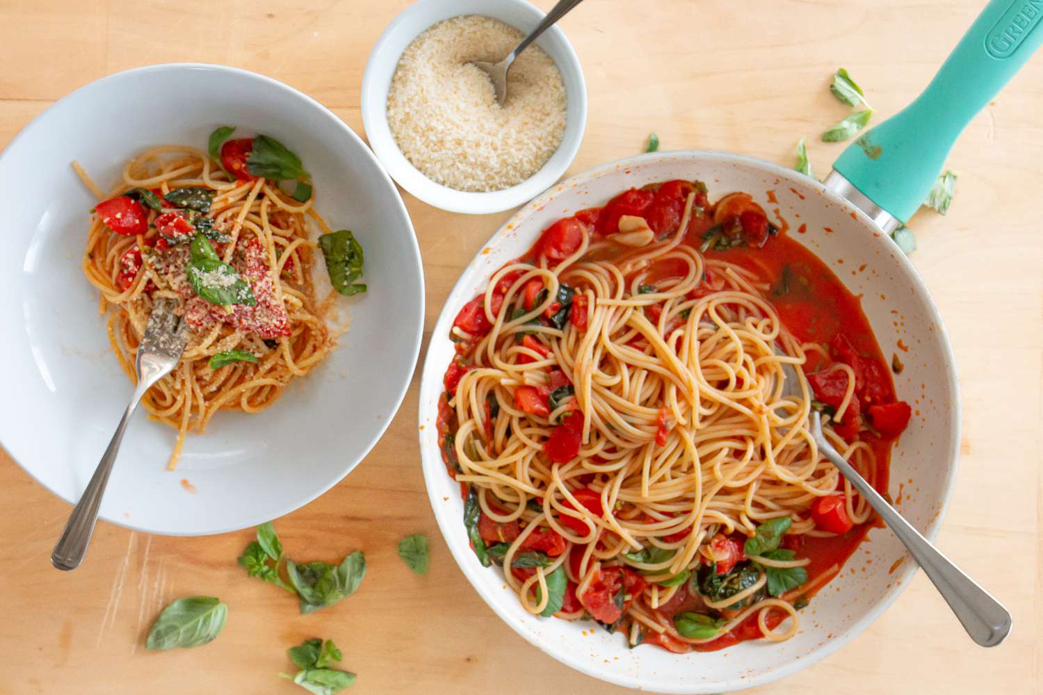 Overhead shot of a pot with spaghetti in tomato sauce next to a bowl with a serving of the pasta garnished with basil