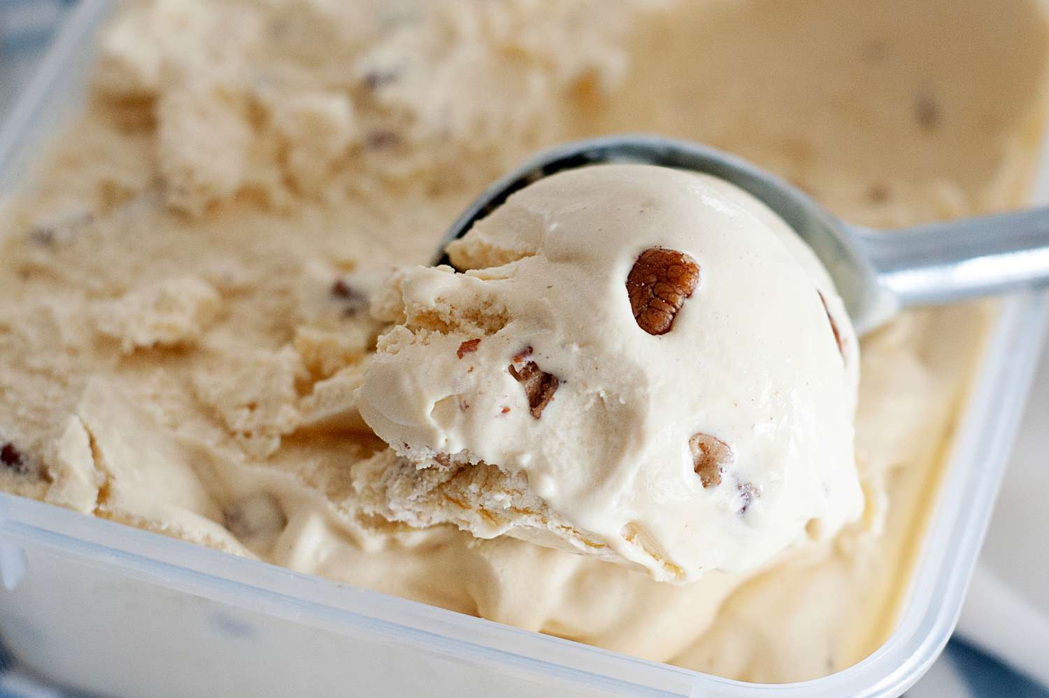 Scooping butter pecan ice cream with an ice cream scoop.