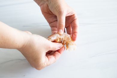 Hands showing how to devein shrimp.