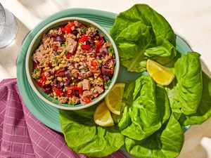 Overhead view of a bowl of italian-style tuna salad on a plate with lemon slices and lettuce