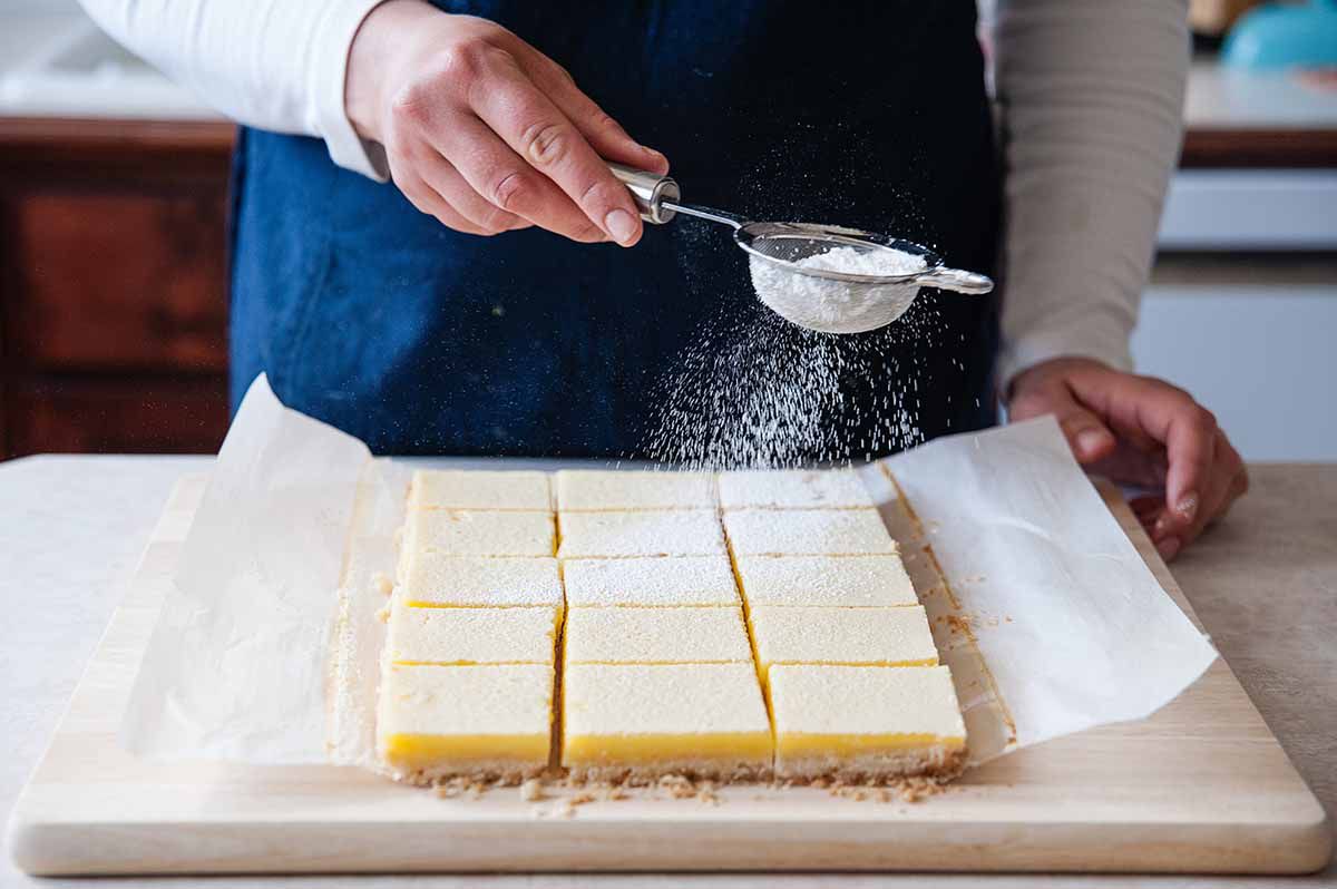 Best Lemon Bars - lemon bars with powdered sugar on cutting board