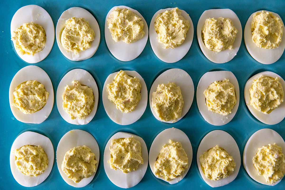 How to Make Deviled Eggs - egg halves filled with creamy yolks on a blue platter