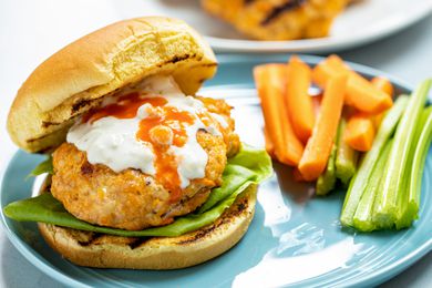 The top bun set to the side of the BEST spicy buffalo chicken burger.
