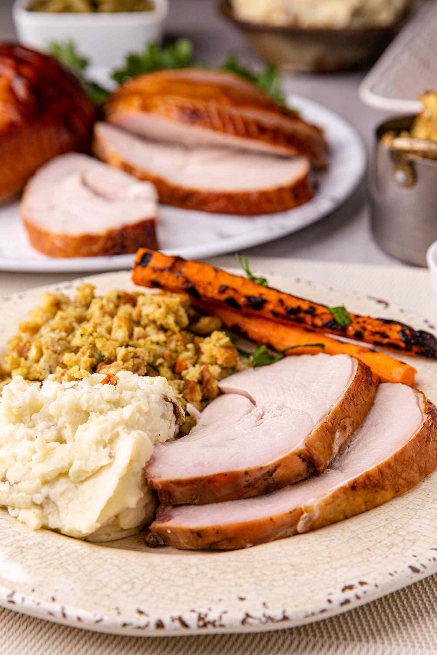 A plate with two slices of apple and sage-brined smoked turkey breast served with vegetable sides.