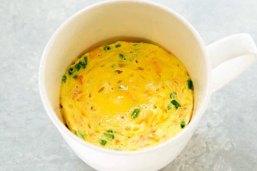 Egg dish cooked in a white mug topped with chopped green herbs