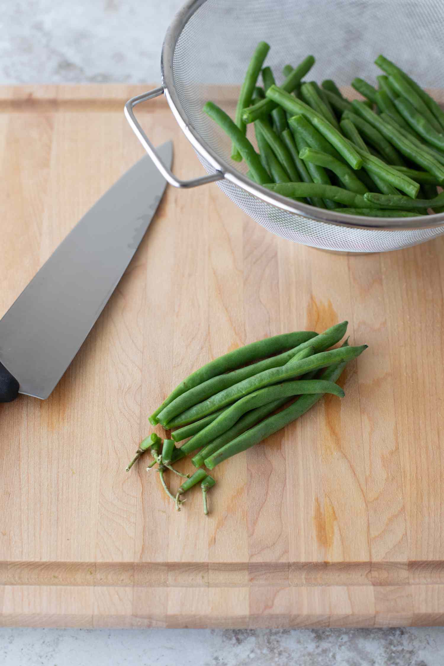 Green beans on a wood cutting board with knife