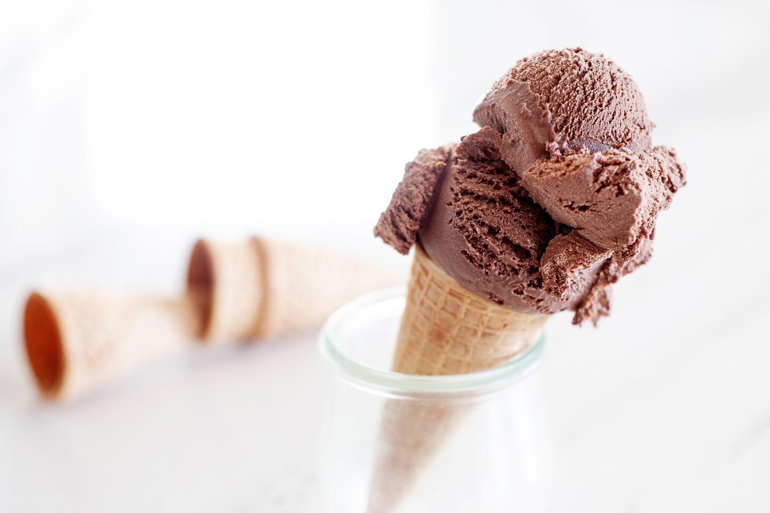 Double scoop of homemade chocolate ice cream cone set in a dish.