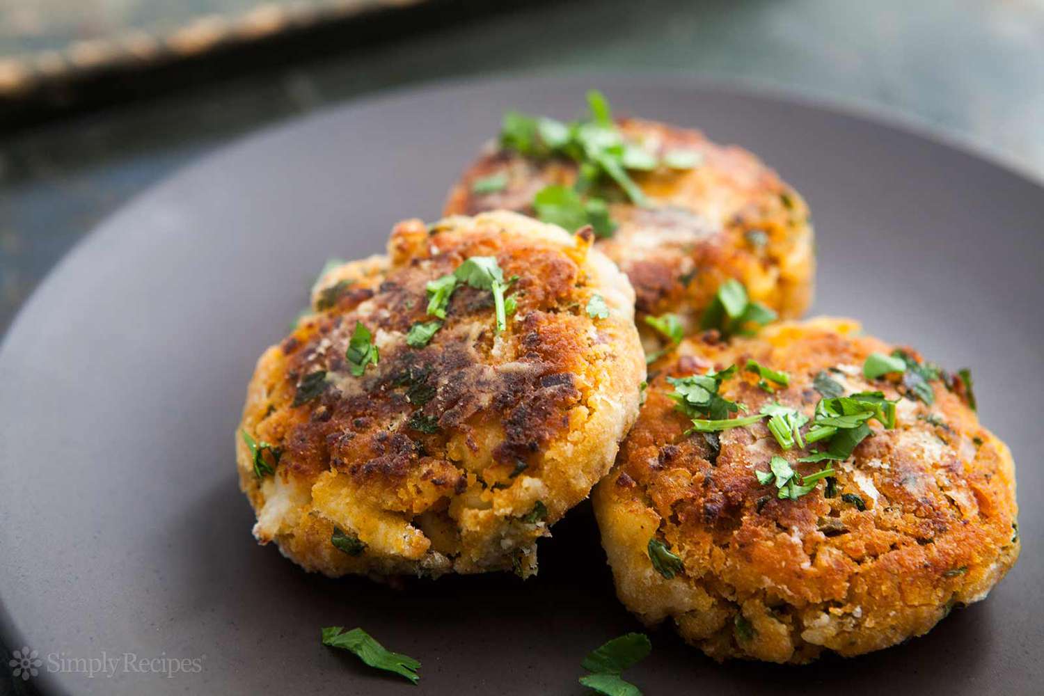 3 shrimp cakes on black plate