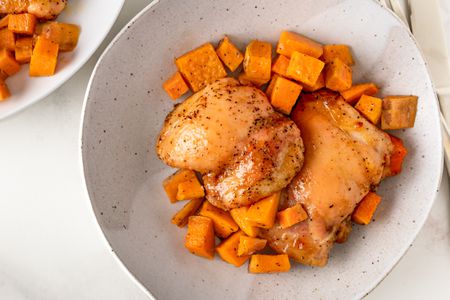 Overhead view of a bowl of roast chicken and cubed sweet potatoes